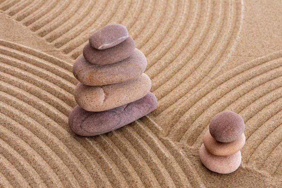 Serene zen stones stacked on raked sand, symbolizing balance and tranquility.