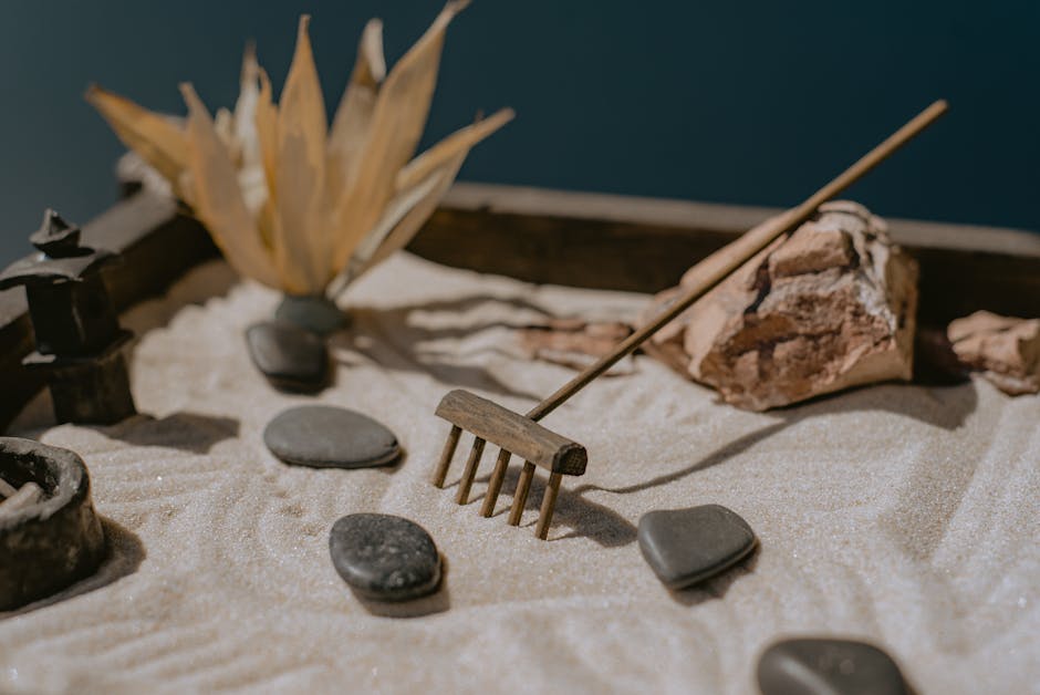 Close-up of a Zen garden with sand, stones, and a miniature rake for meditation.