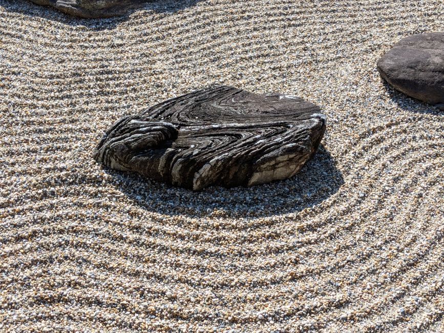 Close-up of a patterned rock in a Zen garden with raked gravel, creating a tranquil atmosphere.